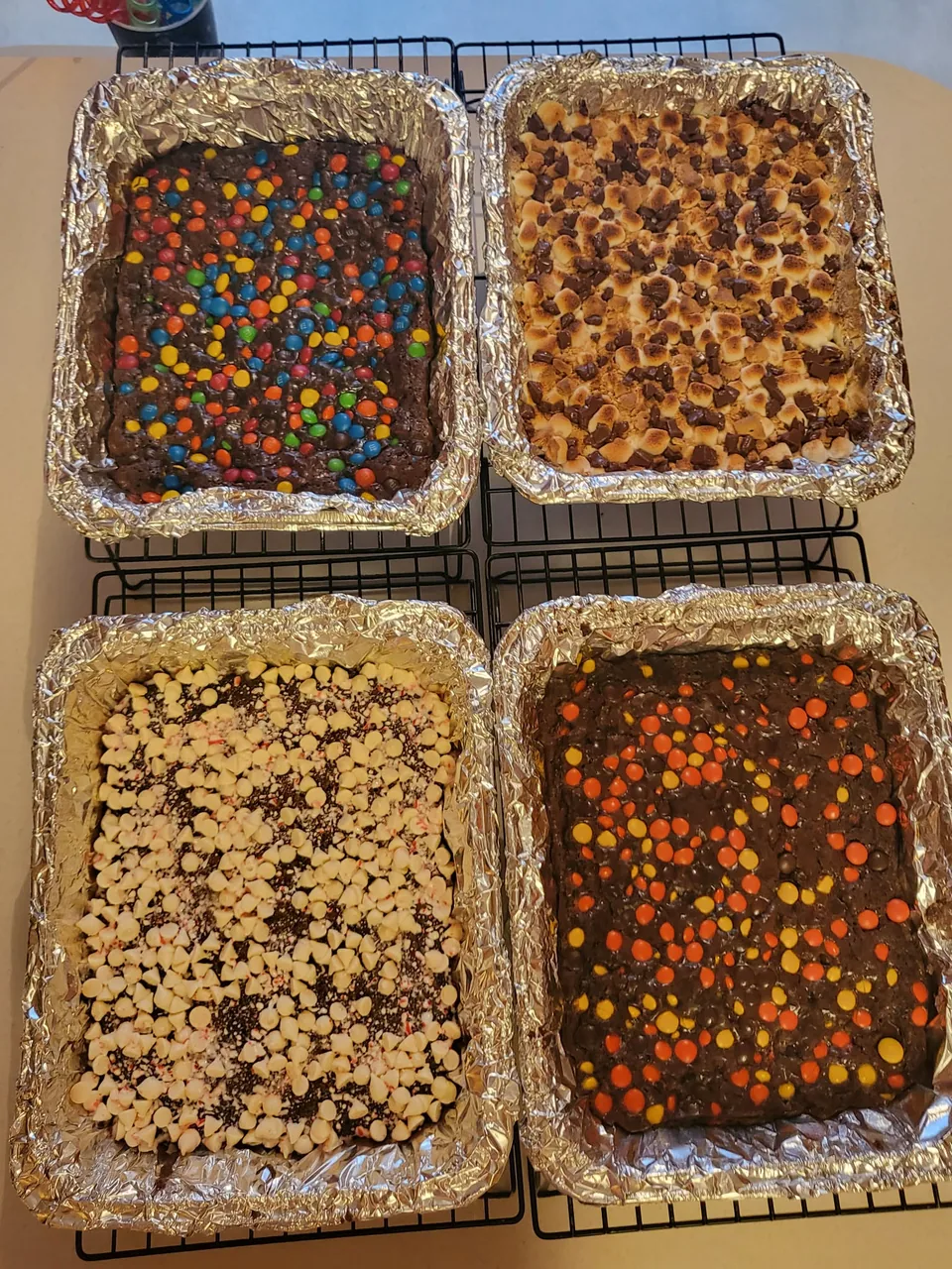 Four pans of brownies finished with assorted toppings