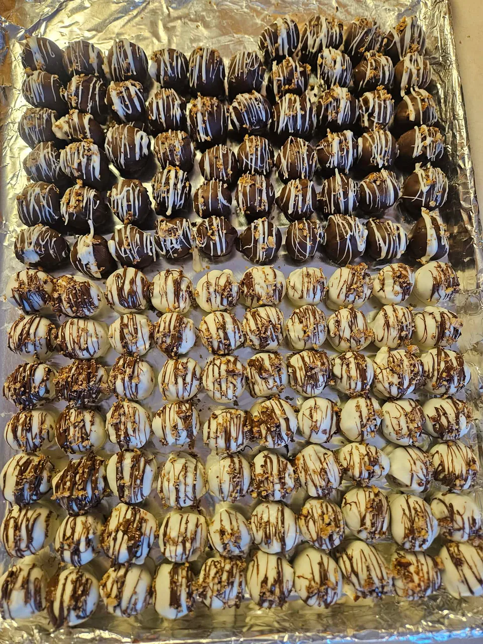 Rows of dark and white chocolate truffles finished with decorative drizzle