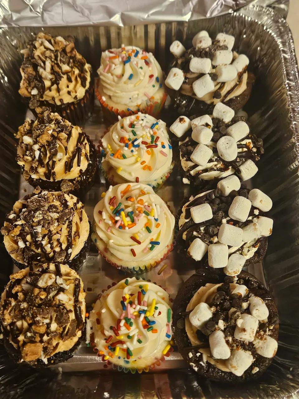 Assortment of cupcakes with chocolate, marshmallow, and sprinkle toppings