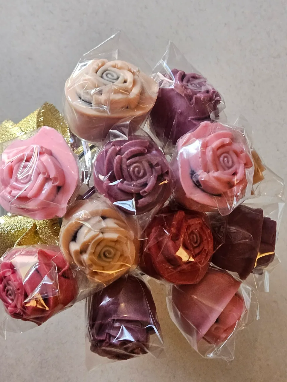 Assorted wrapped rose-shaped cake pops in pink and purple tones