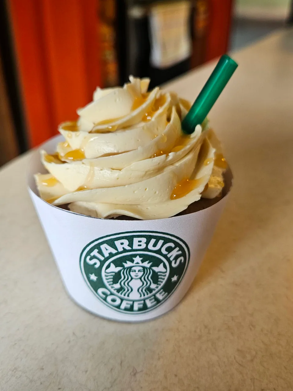 Close-up of a caramel frappuccino cupcake with piped frosting and caramel drizzle