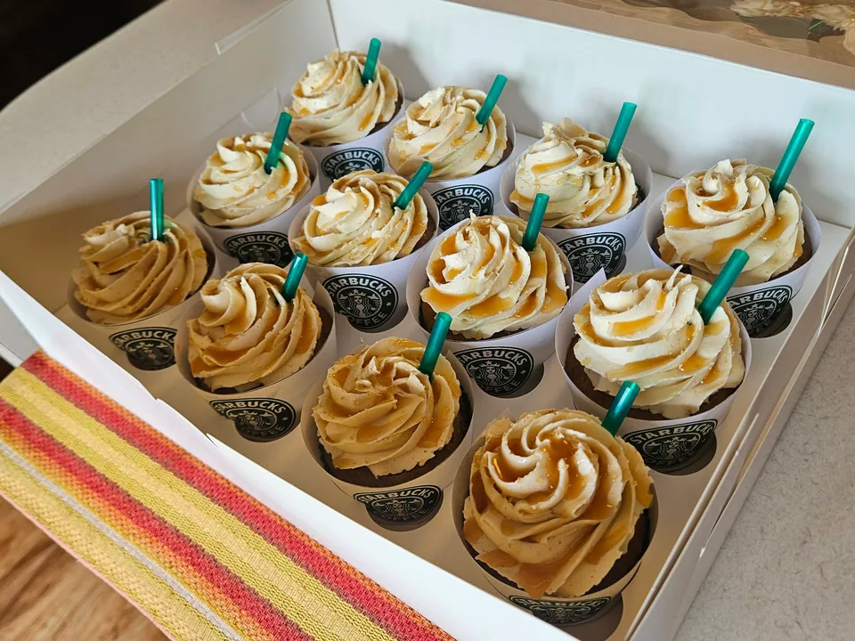 Tray of coffeehouse-style cupcakes with caramel frosting and green straws