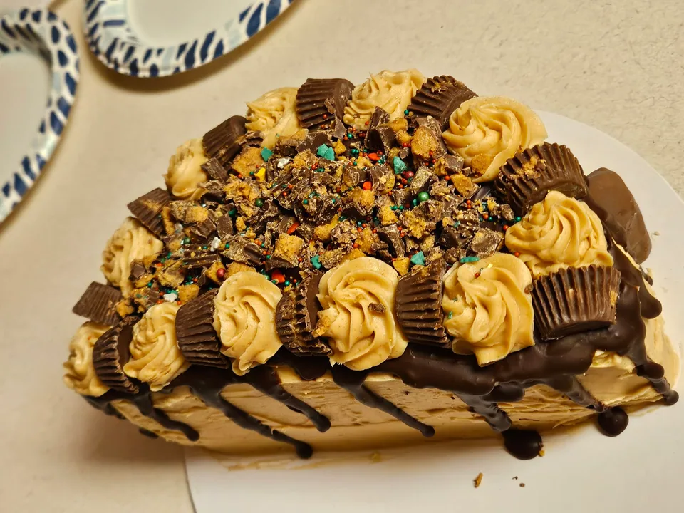 Chocolate cake with piped caramel frosting, chocolate drizzle, and candy pieces