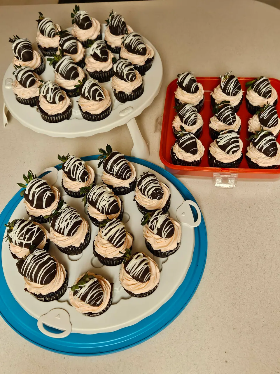 Large spread of chocolate covered strawberry cupcakes with contrasting drizzle