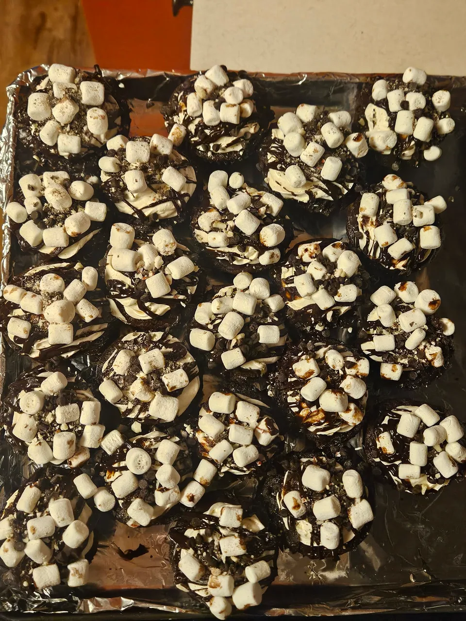 Tray of chocolate brownies topped with marshmallows and chocolate drizzle