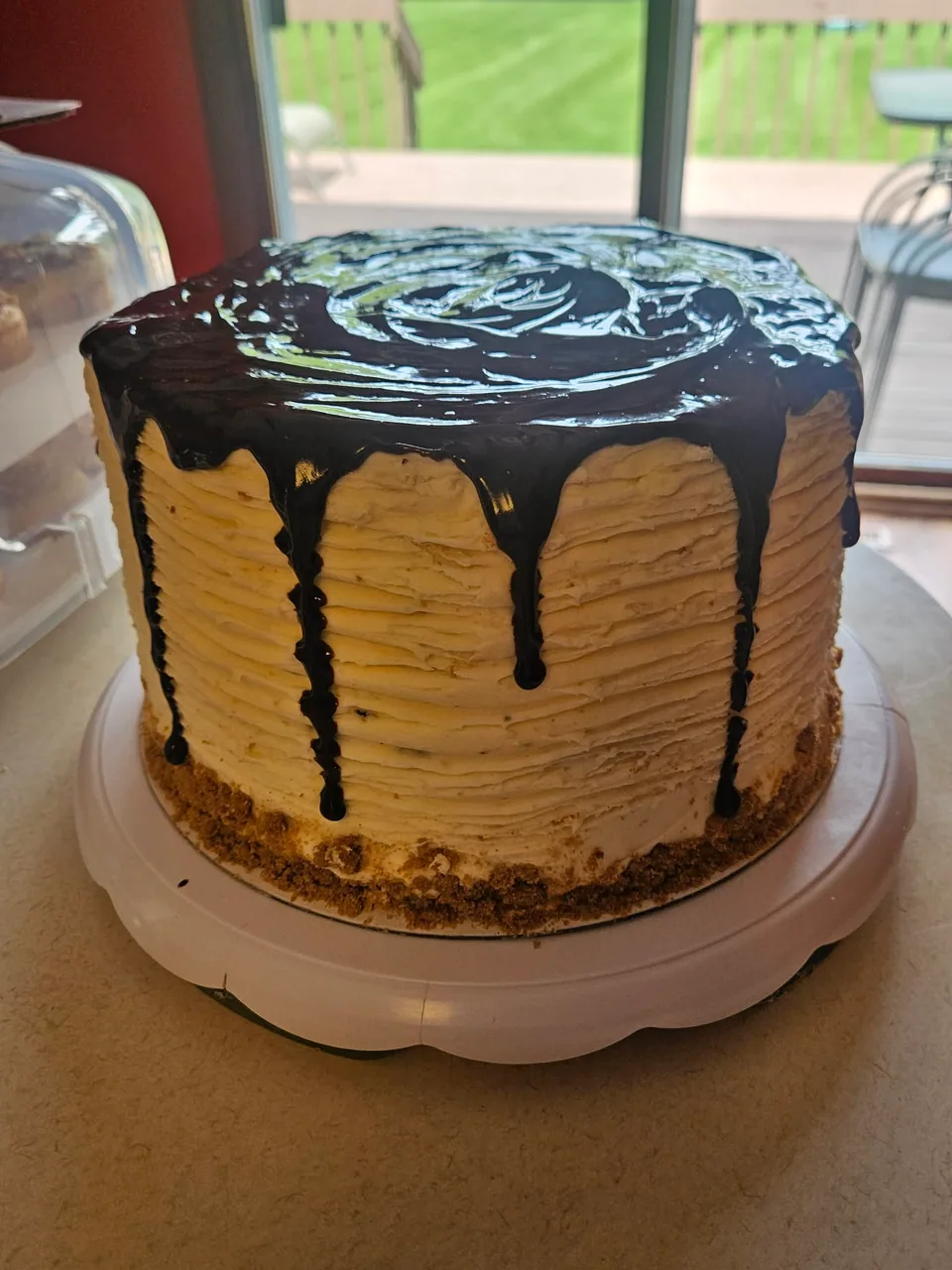 Tall caramel-colored cake finished with glossy dark chocolate drip