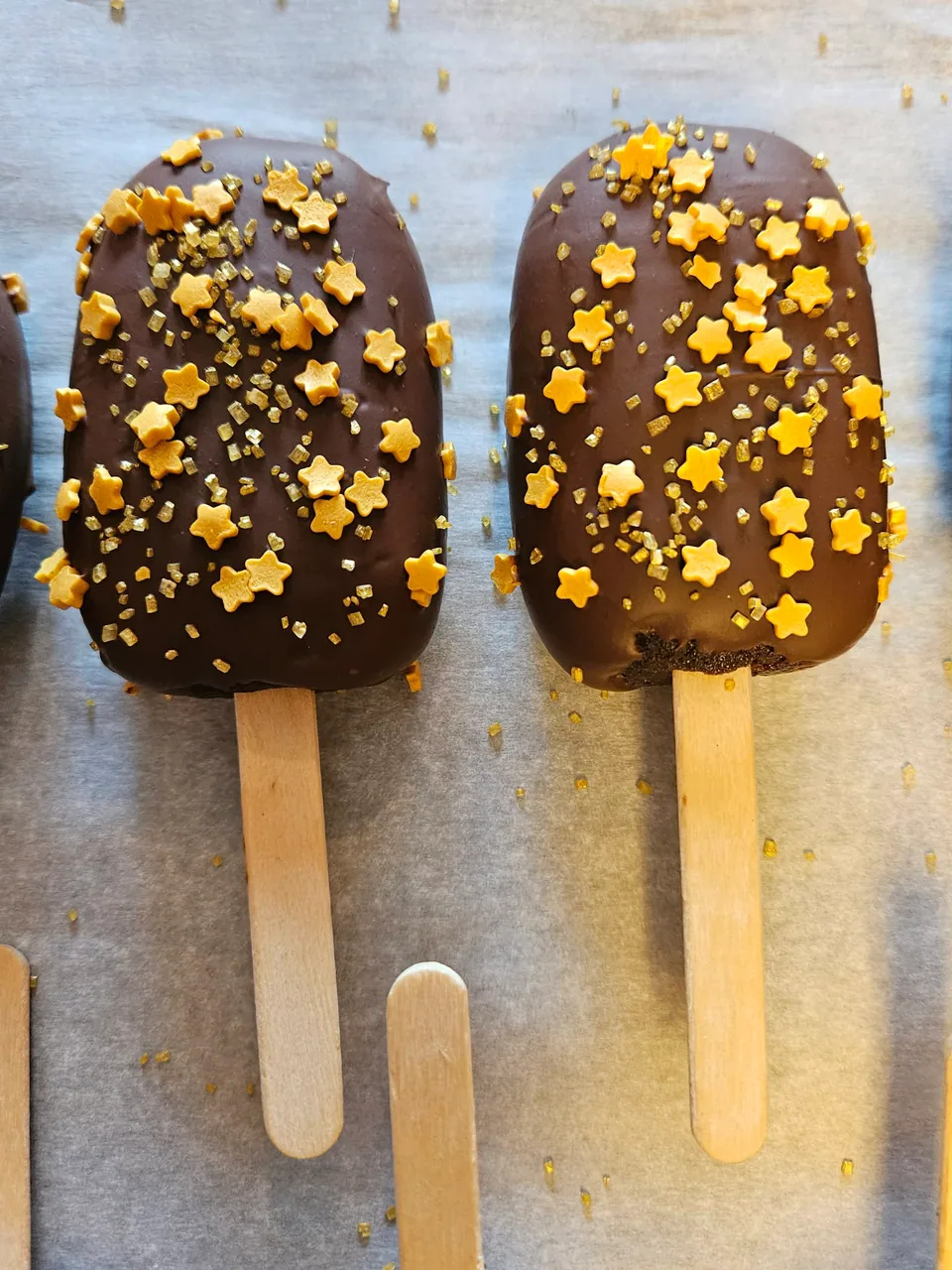 Pair of chocolate-dipped cake pops decorated with gold stars