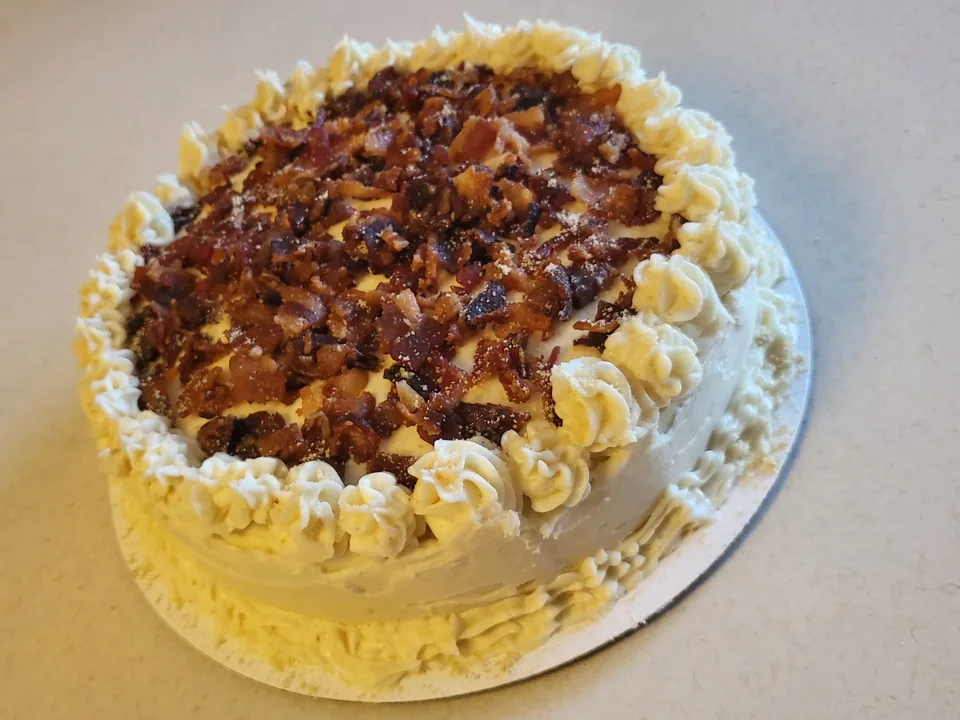 Round cream-frosted cake with piped border and a textured topping