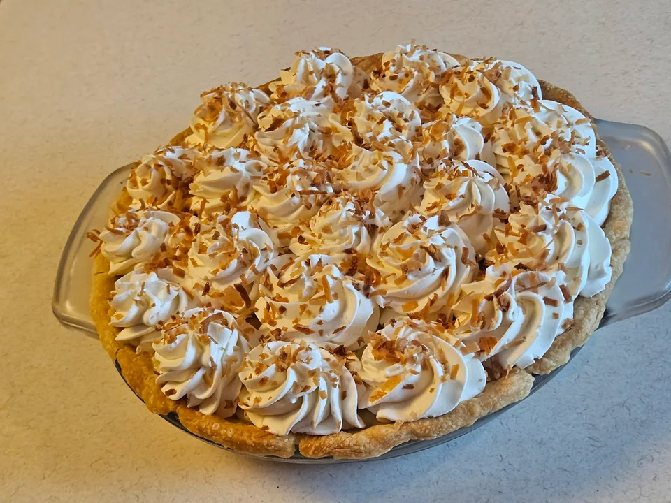Round dessert pie with piped cream and a caramel-colored drizzle