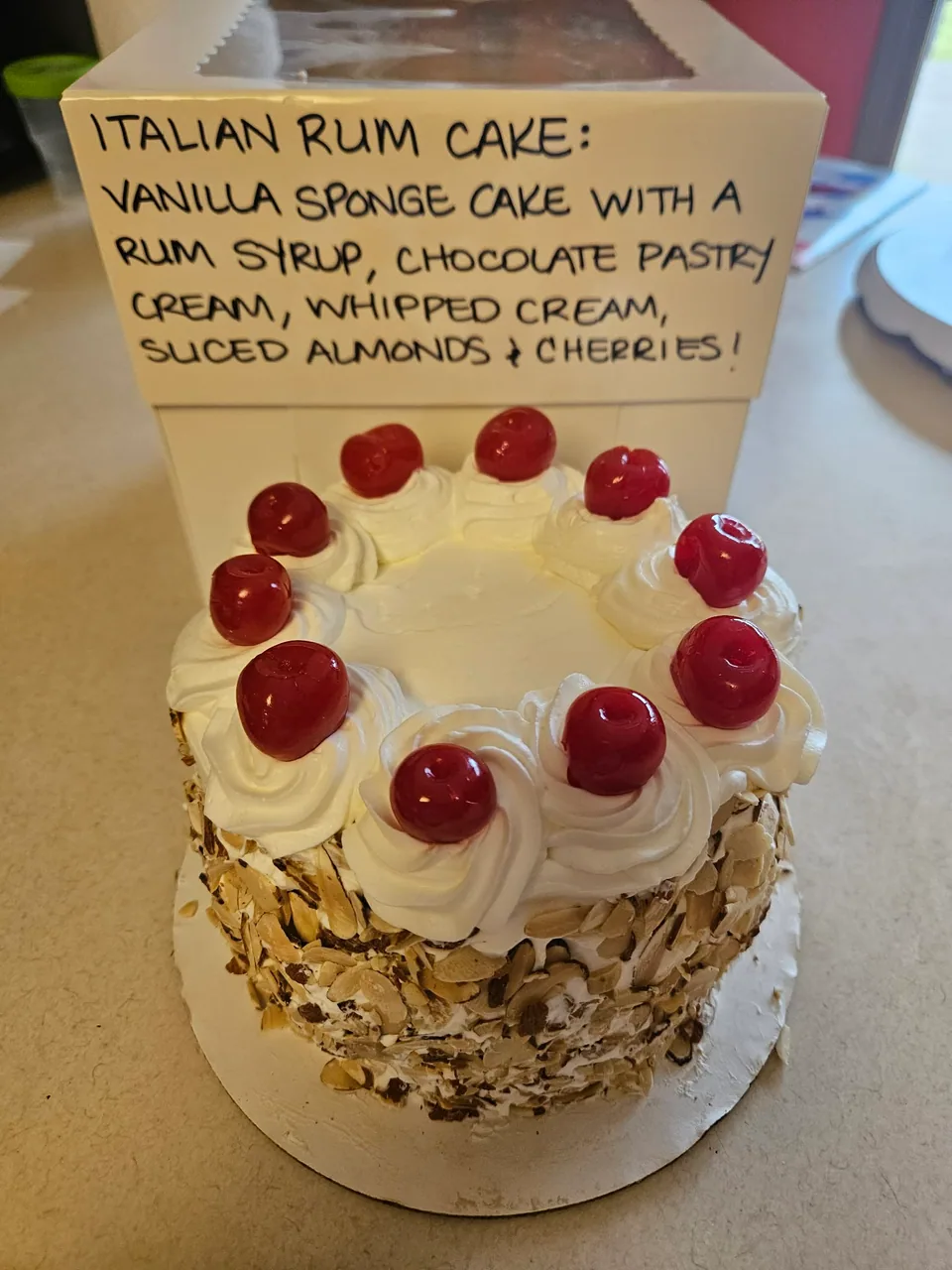 Italian rum cake with piped cream, cherries, and chopped nuts