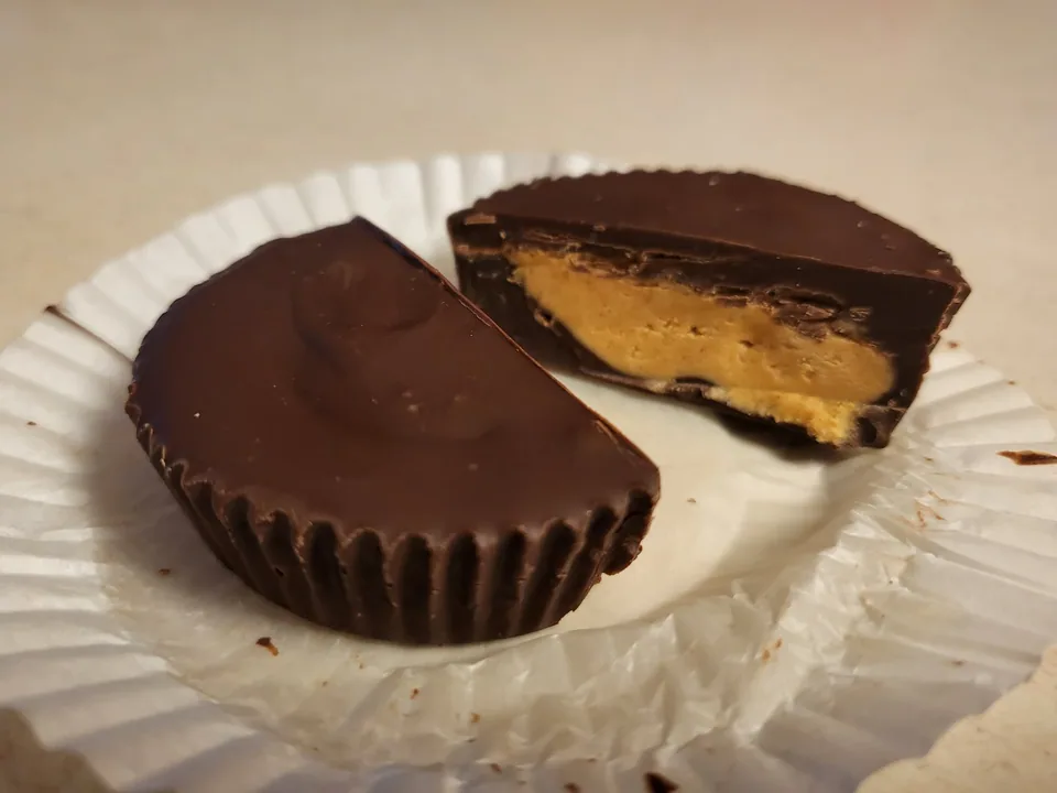 Finished chocolate peanut butter cups with one cut open to show the filling