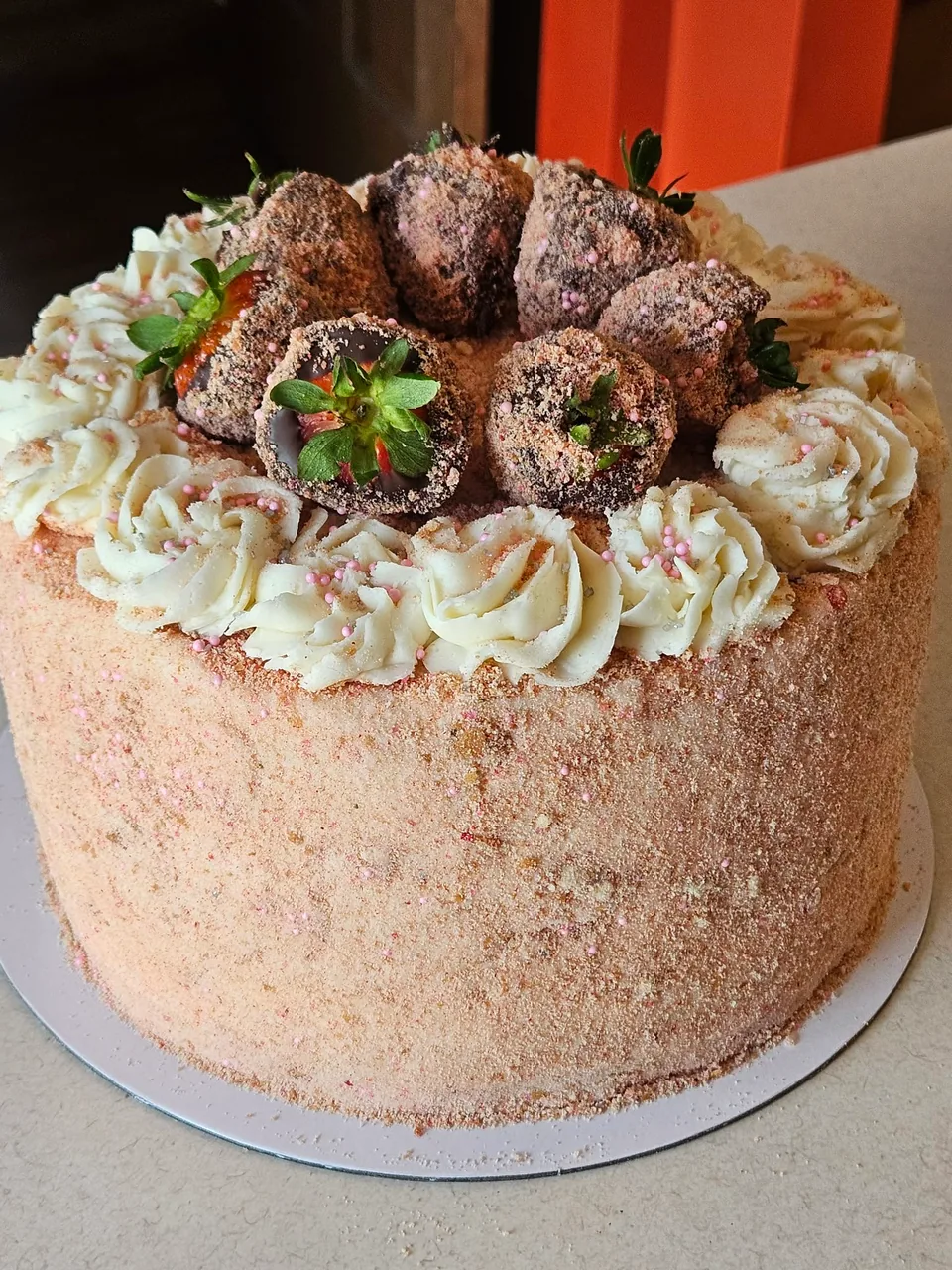 Pink frosted berry cake topped with fresh strawberries