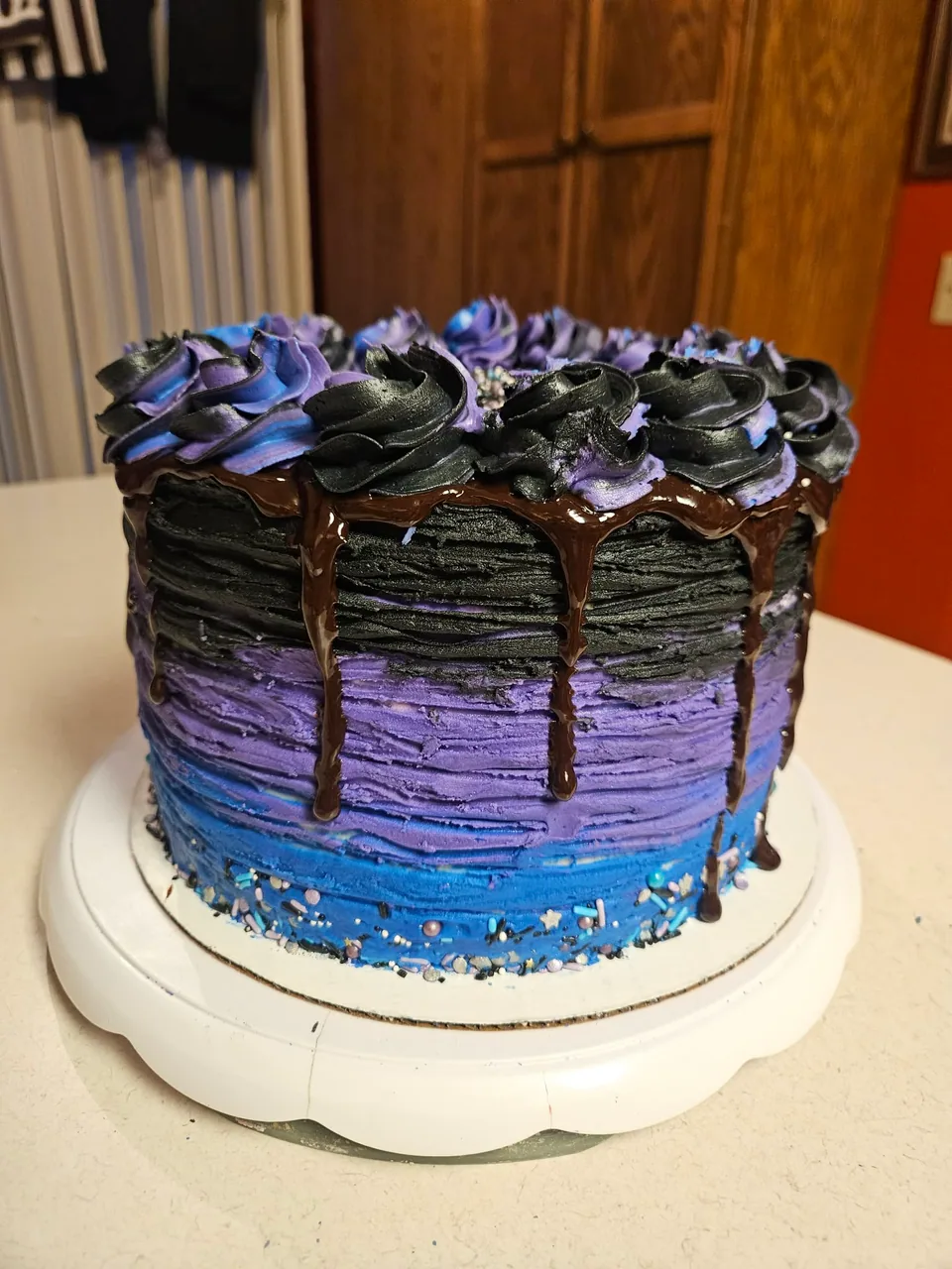 Purple and blue celebration cake with chocolate drip and sprinkles