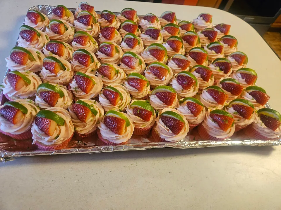 Tray of strawberry lime cupcakes topped with sliced strawberries