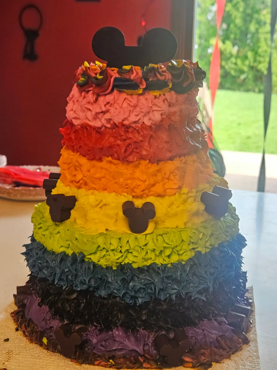 Tall rainbow-striped celebration cake with black decorative accents