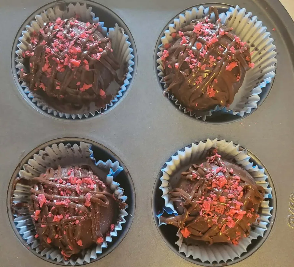 Raspberry hot chocolate bombs with chocolate drizzle and pink decorations