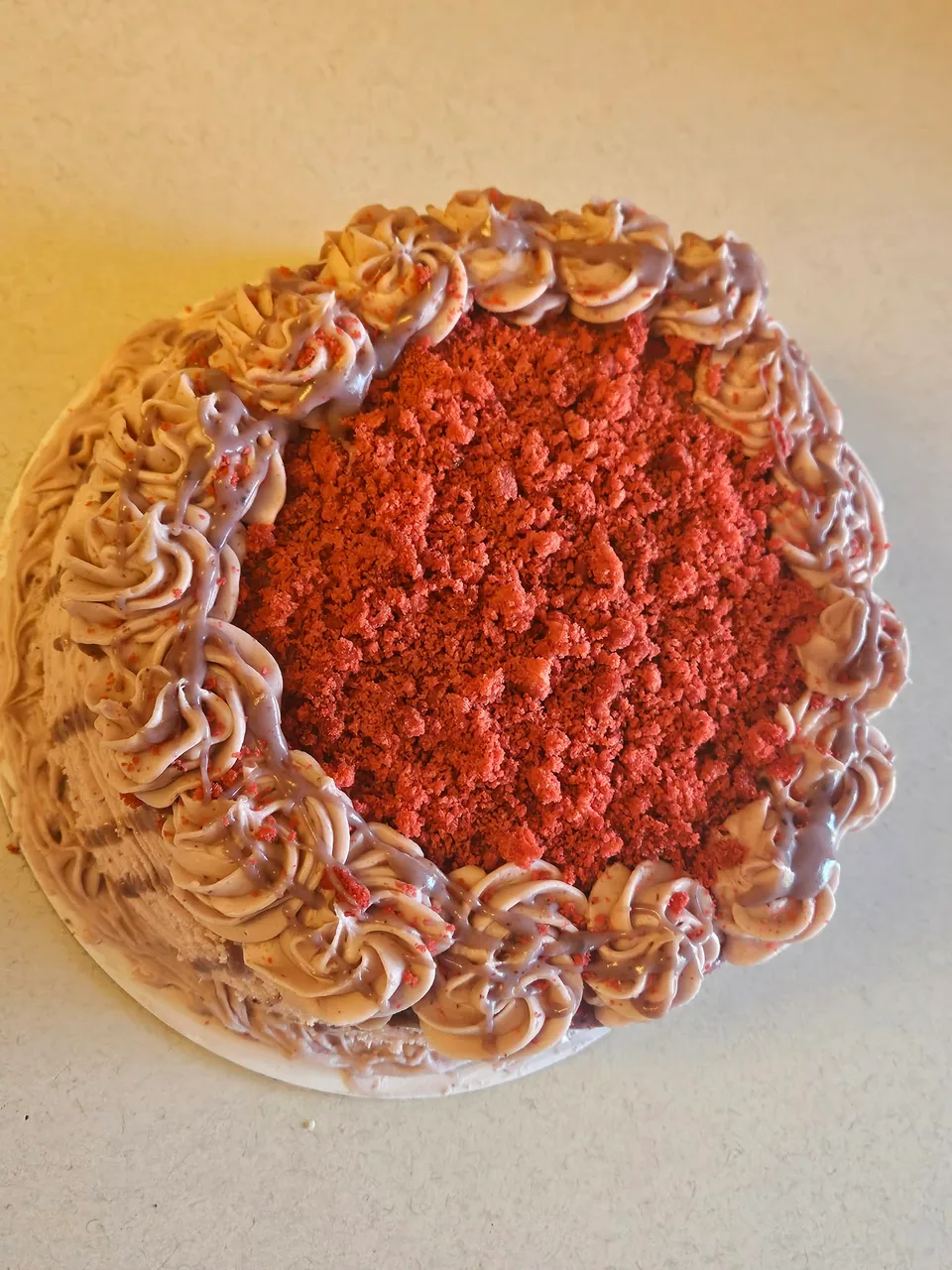 Red velvet cake with piped frosting and a red velvet crumb topping