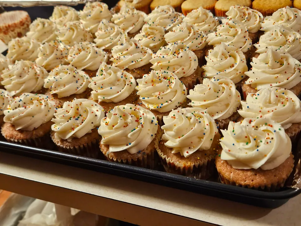 Large tray of cupcakes with piped frosting and colorful sprinkles