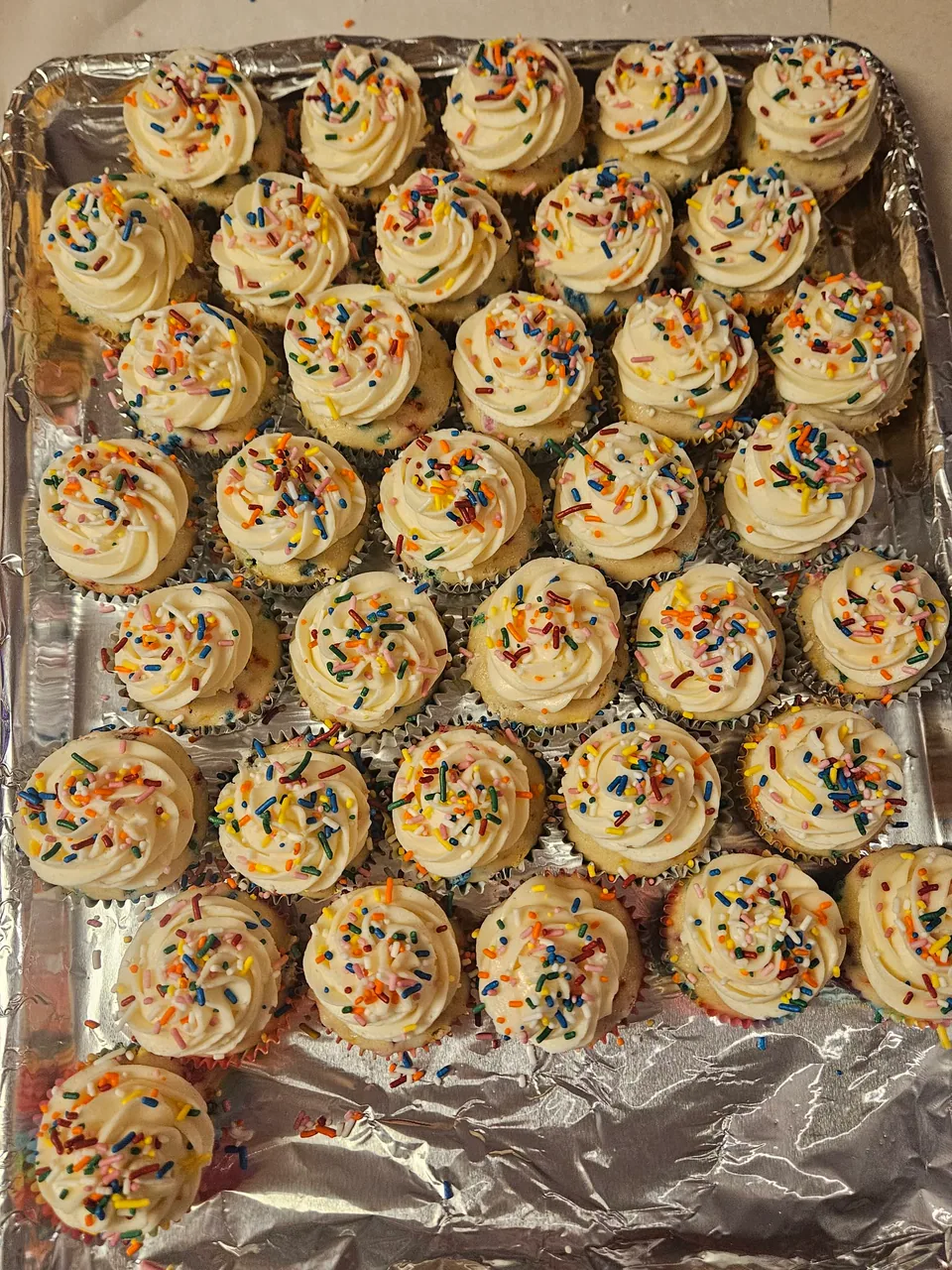 Tray of cupcakes with piped frosting and colorful sprinkles