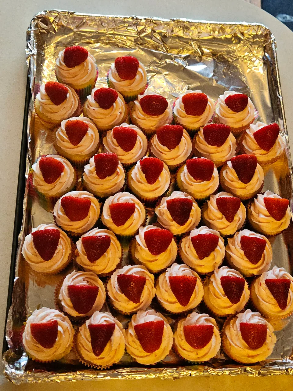 Tray of mini cupcakes topped with strawberries and piped cream