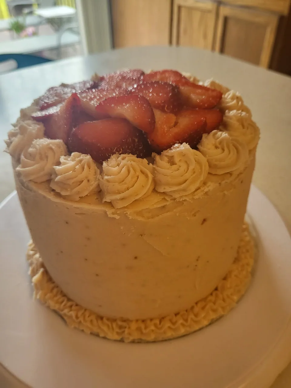 Small round cake topped with fresh strawberries and piped frosting