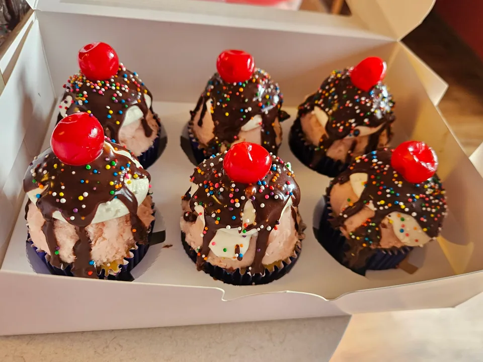 Chocolate sundae cupcakes with cherries, drizzle, sprinkles, and nuts