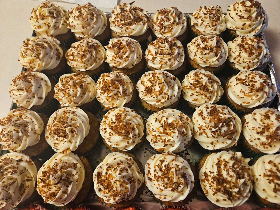 Tray of cupcakes topped with cream frosting and toasted coconut