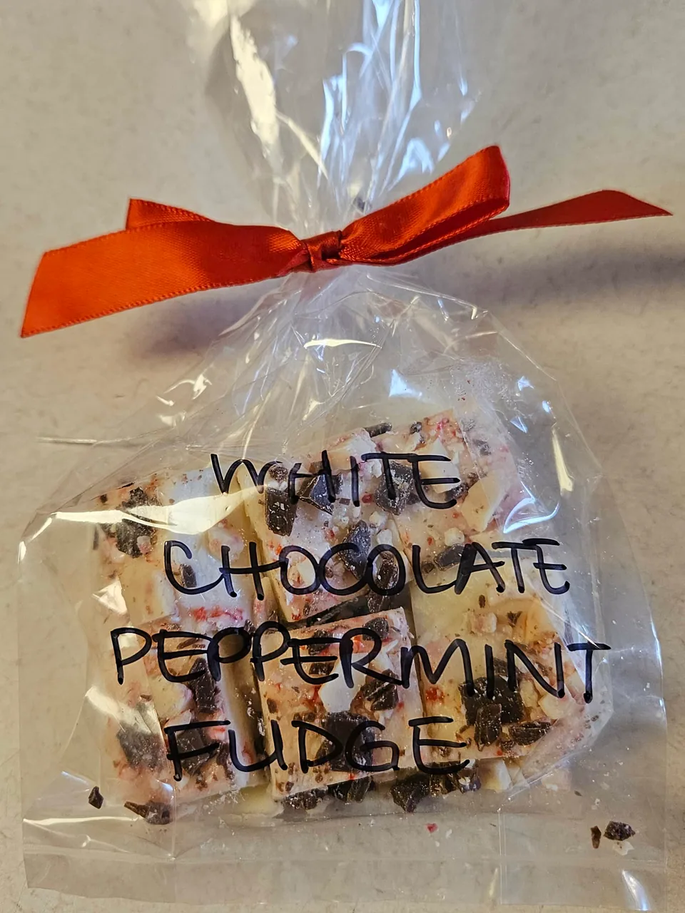 Gift bag of white chocolate peppermint fudge tied with a red bow