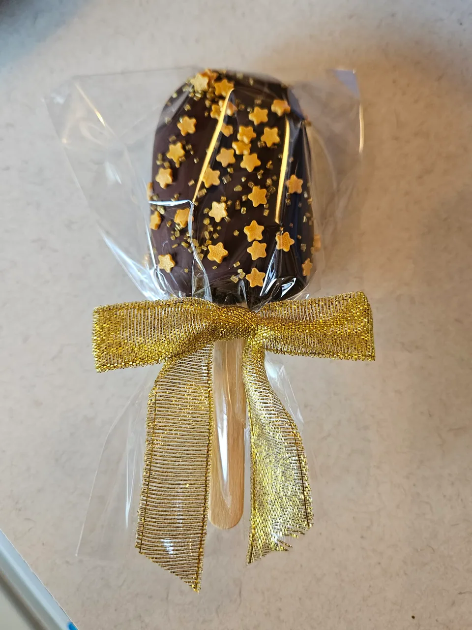 Individually wrapped chocolate cake pop tied with a gold bow